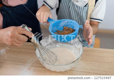 Family Cooking Together. A mother and son preparing a recipe in the kitchen, fostering bonding through baking. 127523497