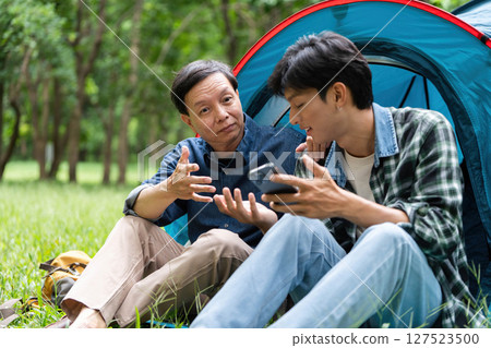 Family interaction during camping. Father and son discussing while relaxing in a tent. Family interaction during camping. Father and son discussing while relaxing in a tent. 127523500