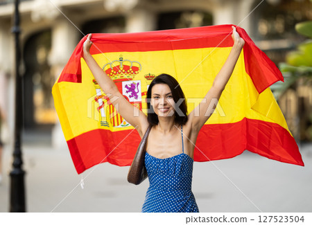 Young woman with spanish flag on city street 127523504