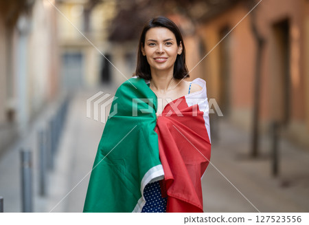 Young woman wrapped in Italian flag on city street Young woman wrapped in Italian flag on city street 127523556