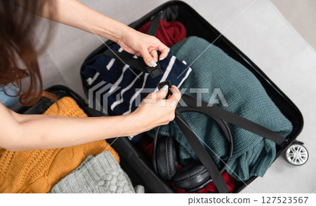 Packing Essentials and Organization. Close-up of a woman securing clothing in her suitcase. 127523567