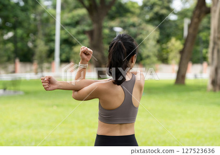 Yoga and stretching. Young woman stretching her arms outdoors in a park. 127523636