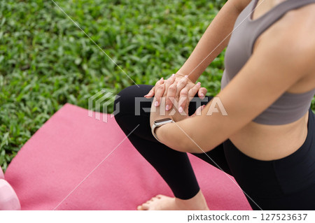 Yoga focus in nature. Close up of a womans hands during a stretch on a yoga mat. 127523637