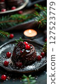 Rich chocolate dessert topped with berries and powdered sugar, styled with candlelight and evergreen decor for a cozy festive feel.  127523779
