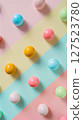 Brightly colored balls or gumballs arranged in a diagonal pattern over pastel-striped background, creating a playful modern design.  127523780