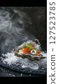 Luxury oyster dish served on crushed ice with roe and a pearl, featuring smoke effects and fine dining presentation.  127523785