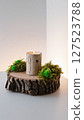 Cozy home decoration featuring a birch style candle on a wood slice base with green moss for a natural rustic touch.  127523788
