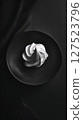 Stylish white swirl dessert plated on a matte black dish with dramatic lighting, showcasing minimalism and gourmet elegance.  127523796