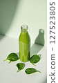 Healthy green smoothie in a glass bottle surrounded by spinach leaves, symbolizing detox, nutrition, and wellness.  127523805