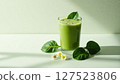 Healthy green smoothie in a glass, surrounded by spinach leaves and small white flowers, symbolizing detox and clean eating.  127523806