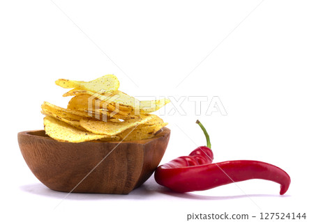 Chips with red pepper on a wooden plate close-up. 127524144