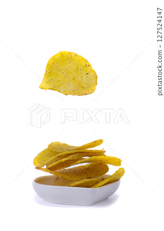 Chips are flying into a small plate on a white background. 127524147