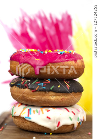 Creative sweet food. A stack of glazed colorful assorted donuts on a bright watercolor painted background. 127524255