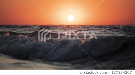 Beautiful sunset over the sea. Red sun and waves. 127524267