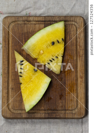 Yellow slice of watermelon on a wooden background. Yellow slice of watermelon on a wooden background. 127524356