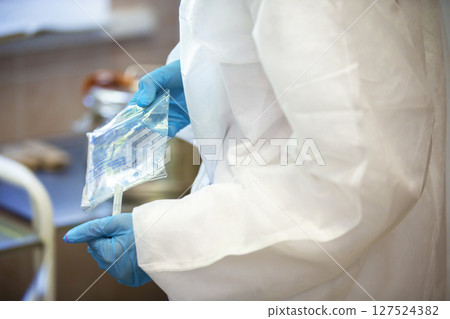 The doctor's hands in rubber gloves hold the dropper solution. The doctor's hands in rubber gloves hold the dropper solution. 127524382