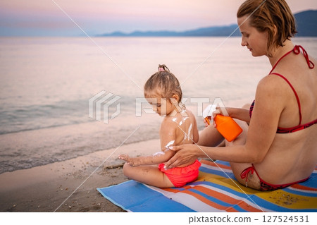 Mother applying sunscreen to child on Greek beach 127524531