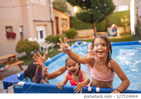 Children playing and enjoying a summer day in a backyard swimming pool Children playing and enjoying a summer day in a backyard swimming pool 127524604