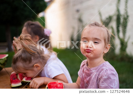Children enjoying a summer picnic with fresh watermelon slices 127524646