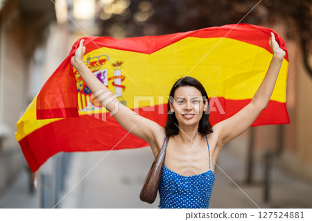 Young woman with spanish flag on city street 127524881