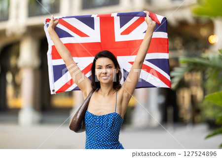 Young girl holding national flag of UK flag, standing outdoors Young girl holding national flag of UK flag, standing outdoors 127524896