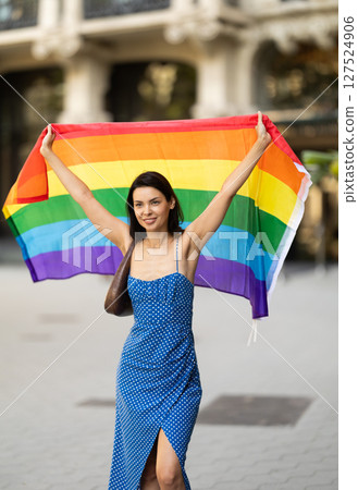 Brunette girl waving LGBT flag on street of city Brunette girl waving LGBT flag on street of city 127524906