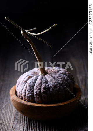 Black Futsu pumpkin with wrinkled skin rests on wooden tabletop Black Futsu pumpkin with wrinkled skin rests on wooden tabletop 127525128