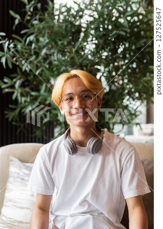 Asian teenager man with blonde hair sitting inside cafe restaurant Asian teenager man with blonde hair sitting inside cafe restaurant 127525647