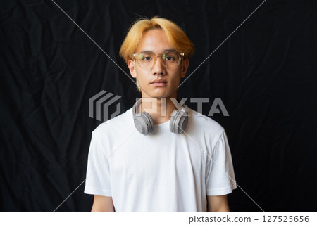 Studio portrait of young gay man with septum piercing ring and headphones Studio portrait of young gay man with septum piercing ring and headphones 127525656
