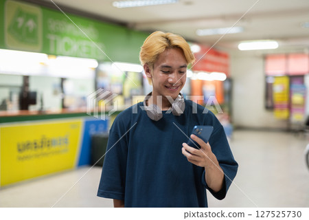 Young Asian tourist man in bus station using phone 127525730