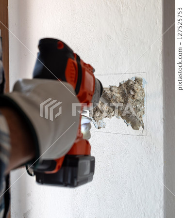 Carpenter electrician working with demolition hammer. Electricity. 127525753