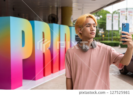 Young gay man taking selfie with phone during pride festival 127525981