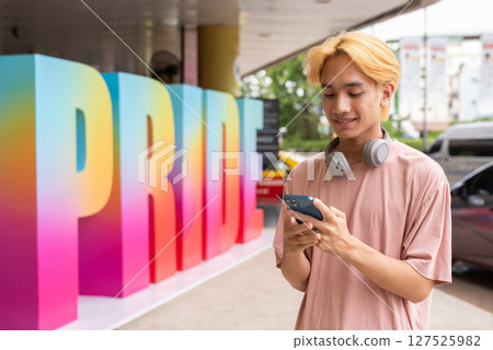 Young gay man using phone during pride festival 127525982