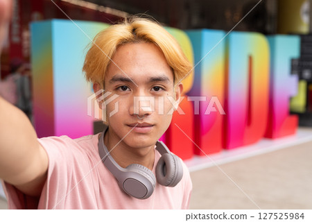 Gay influencer taking selfie during pride outdoors in city 127525984