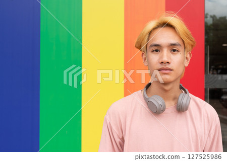 Handsome gay man portrait against pride rainbow background Handsome gay man portrait against pride rainbow background 127525986