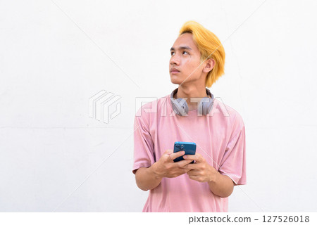 Man using smartphone against white wall Man using smartphone against white wall 127526018