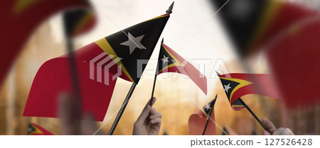 East Timor flags in their hands on a blurred urban background 127526428