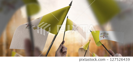 Vatican flags in their hands on a blurred urban background 127526439