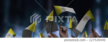 Vatican flags in their hands on a blurred urban background 127526440