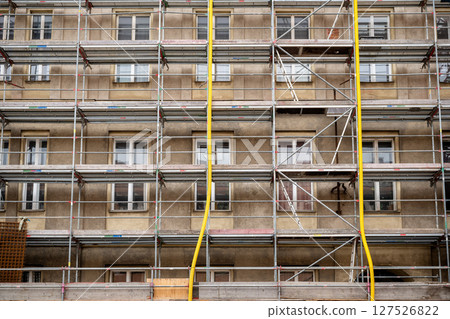 Old residential building facade with metal scaffolding, concept of construction and renovation site Old residential building facade with metal scaffolding, concept of construction and renovation site 127526822