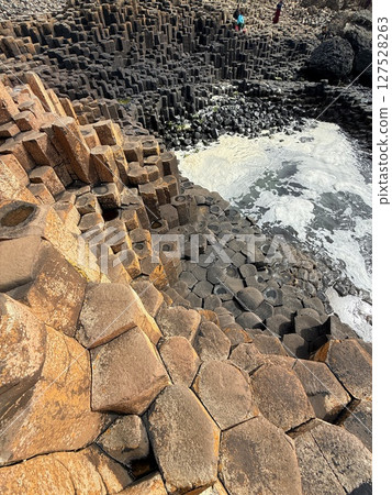 Giant's Causeway is a UNESCO World Heritage Site on Northern Ireland's Antrim Coast, famous for hexagonal stones by volcanic activity and beautiful coast. 127528263