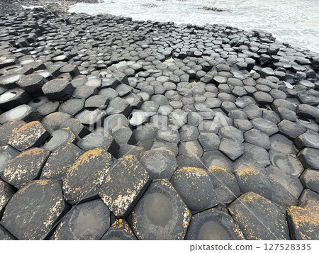 Giant's Causeway is a UNESCO World Heritage Site on Northern Ireland's Antrim Coast, famous for hexagonal stones by volcanic activity and beautiful coast. 127528335