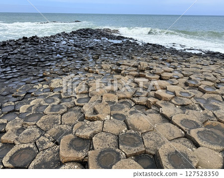 Giant's Causeway is a UNESCO World Heritage Site on Northern Ireland's Antrim Coast, famous for hexagonal stones by volcanic activity and beautiful coast. 127528350
