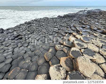 Giant's Causeway is a UNESCO World Heritage Site on Northern Ireland's Antrim Coast, famous for hexagonal stones by volcanic activity and beautiful coast. 127528354