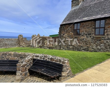 Dunluce Castle, perched on Northern Ireland's rugged Antrim Coast, showcases dramatic medieval ruins against windswept cliffs. Its weathered stone walls and sea views evoke history and mystery, ideal  127528383