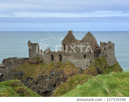 Dunluce Castle, perched on Northern Ireland's rugged Antrim Coast, showcases dramatic medieval ruins against windswept cliffs. Its weathered stone walls and sea views evoke history and mystery, ideal Dunluce Castle, perched on Northern Ireland's rugged Antrim Coast, showcases dramatic medieval ruins against windswept cliffs. Its weathered stone walls and sea views evoke history and mystery, ideal 127528386