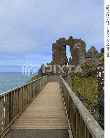Dunluce Castle, perched on Northern Ireland's rugged Antrim Coast, showcases dramatic medieval ruins against windswept cliffs. Its weathered stone walls and sea views evoke history and mystery, ideal  127528393