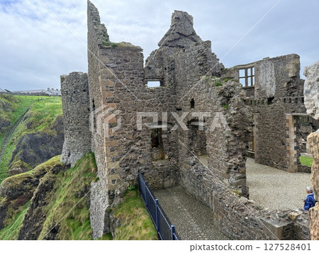 Dunluce Castle, perched on Northern Ireland's rugged Antrim Coast, showcases dramatic medieval ruins against windswept cliffs. Its weathered stone walls and sea views evoke history and mystery, ideal  127528401