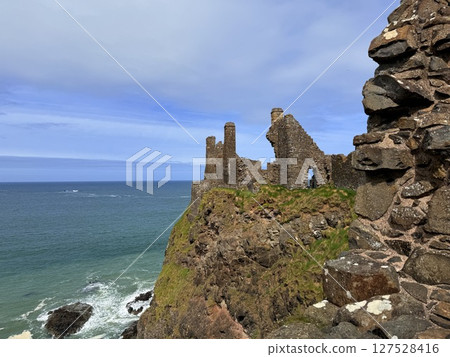Dunluce Castle, perched on Northern Ireland's rugged Antrim Coast, showcases dramatic medieval ruins against windswept cliffs. Its weathered stone walls and sea views evoke history and mystery, ideal  127528416