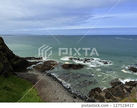 Dunluce Castle, perched on Northern Ireland's rugged Antrim Coast, showcases dramatic medieval ruins against windswept cliffs. Its weathered stone walls and sea views evoke history and mystery, ideal  127528417